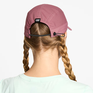 back view of the ciele athletics FTSCap unisex running hat with a curved brim in deco rose color, on a model