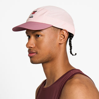 side view of the ciele athletics GOCap with a curved brim unisex running hat in peachskin color, on a model