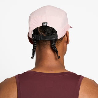 back view of the ciele athletics GOCap with a curved brim unisex running hat in peachskin color, on a model