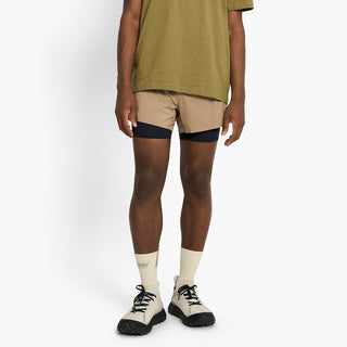 person wearing tan athletic shorts and beige socks on a white background